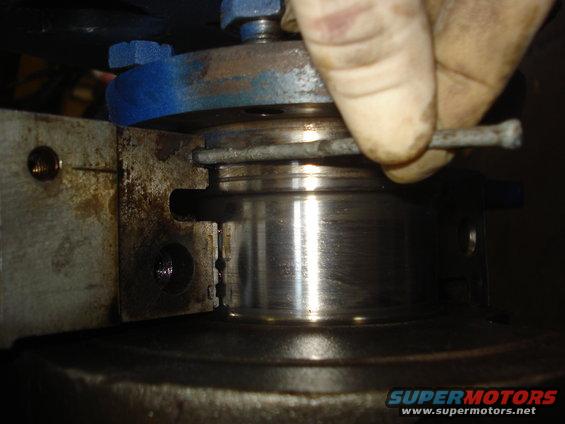 Close-up of engine part with a hand holding a tool