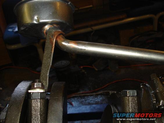 Close-up of an engine oil pan with a metal pickup tube attached. Some rust is visible on the tube