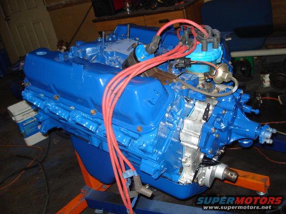 Blue V8 engine on an orange stand, with red spark plug wires