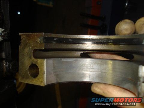 Engine bearing with visible wear and oil residue. Supermotors.net logo visible