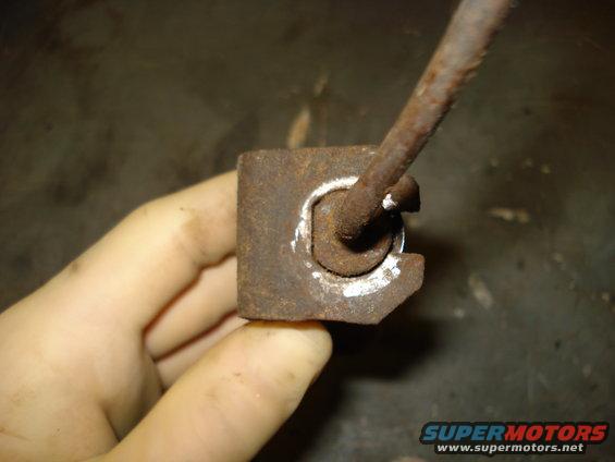 Hand holding rusty metal brake part with a metal rod inserted