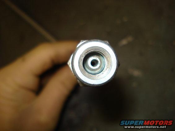 Close-up of a metal brake line fitting held by a hand