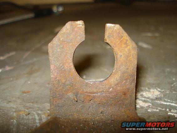 close-up of a rusty metal bracket with a circular cutout and two prongs