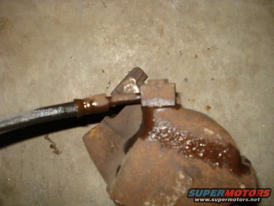 rusted brake caliper and hose assembly on concrete floor