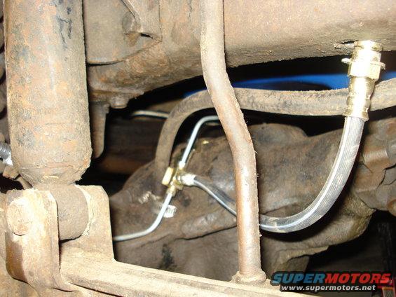 Close-up of rear axle brake lines and shock absorber assembly with rusty metal components