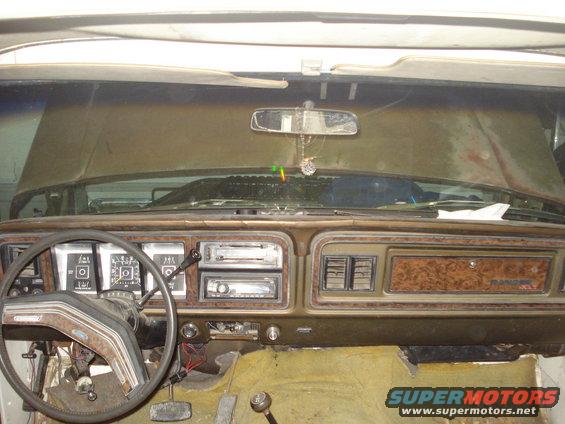 Interior shot of a truck dashboard with wood grain trim and a steering wheel. The word RANGER is visible on the dash