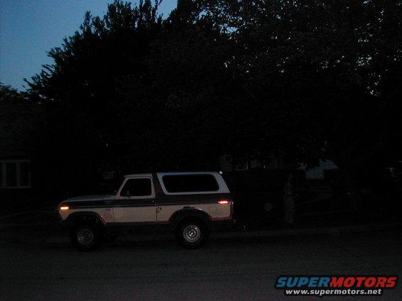Two-tone white and brown 1978 Ford Bronco parked on asphalt at dusk, side view