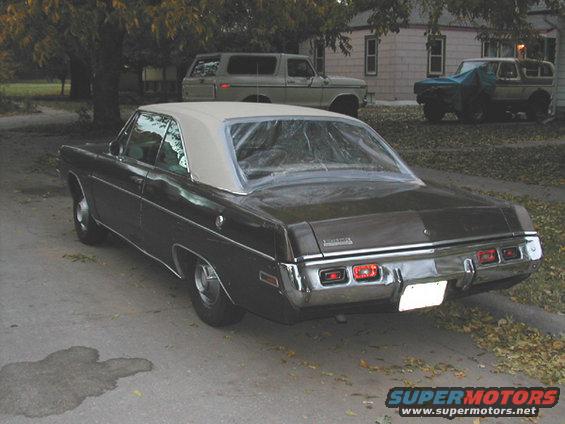 1971 Dodge Dart parked on street, two SUVs in background