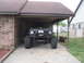 1984 Ford Bronco II - Modified Ford Bronco II with large tires and a custom front bumper sits in a carport.