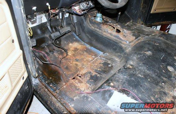 Vehicle interior floor with extensive rust and exposed wires