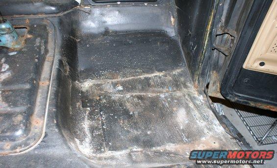 Interior floor of a vehicle showing rust and wear after seat and carpet removal