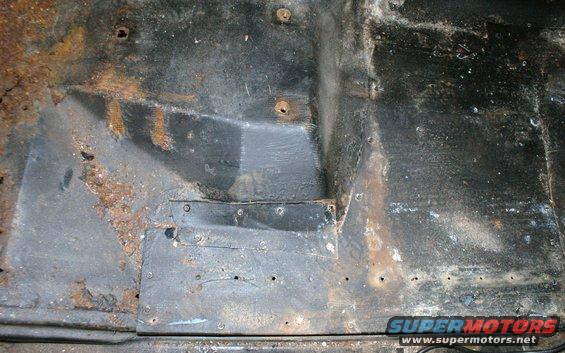 Interior floor pan with significant rust and some patched metal