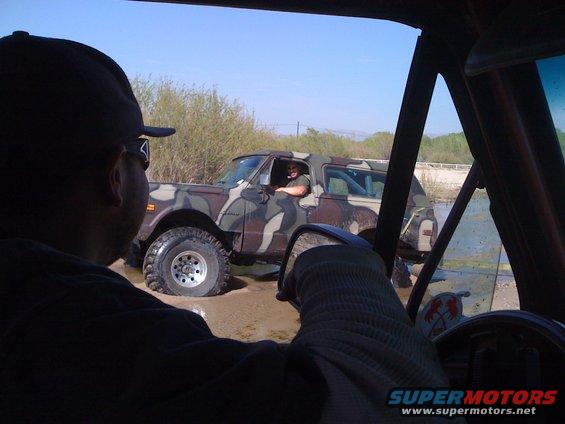 Camouflage SUV stuck in mud, viewed from inside another vehicle
