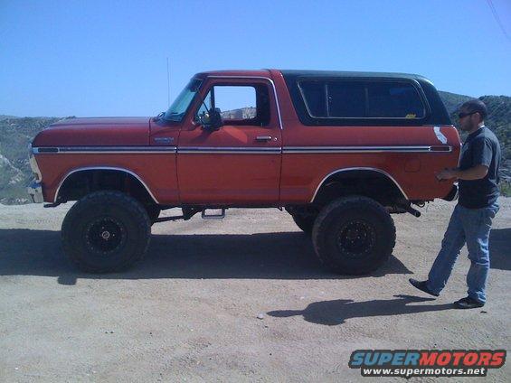 Side view of a lifted 1978 Ford Bronco with a man standing next to it