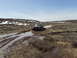 1989 Ford Bronco - A dark SUV navigates a muddy trail in a desolate, off-road environment under a clear blue sky.