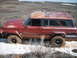 1989 Ford Bronco - This red Jeep Cherokee Chief is stuck in a muddy, snowy terrain, showing signs of wear and tear.
