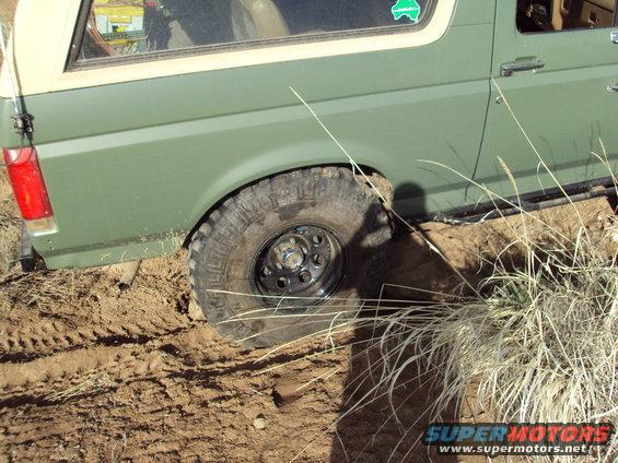 1989 Ford Bronco side view, green with off-road tires stuck in mud