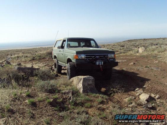 Green Ford Bronco with aftermarket bumper and winch on rocky terrain