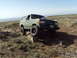1989 Ford Bronco - A modified 1987 Ford Bronco navigates rocky terrain under a clear blue sky.