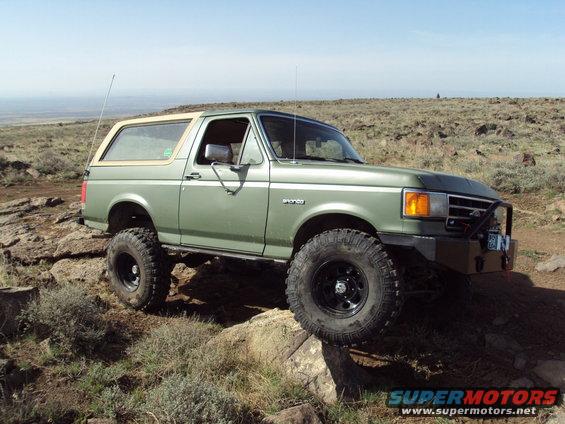 Green 1989 Ford Bronco with tan top on rocky terrain