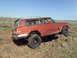 1989 Ford Bronco - A Jeep Cherokee Chief is shown off-roading on a rocky trail under a clear blue sky.
