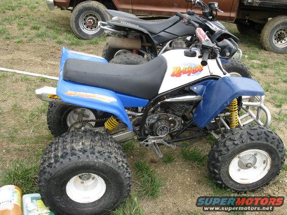 Blue and white all-terrain vehicle with yellow shocks and knobby tires, parked outdoors