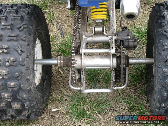 ATV rear axle with chain drive, yellow shock absorber, and knobby tires