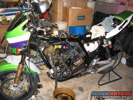 Green and white motorcycle disassembled on a stand