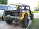 1973 Ford Bronco - This modified off-road vehicle, possibly a Ford Bronco, is seen from the rear with a custom roll cage and large tires.