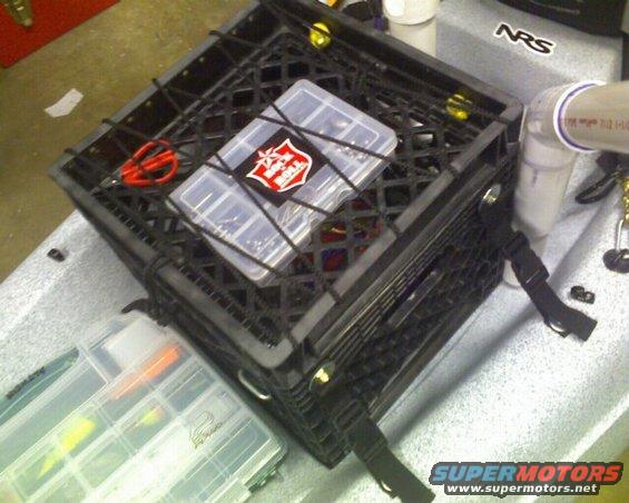 Fishing tackle box and crate secured with bungee cords on a kayak