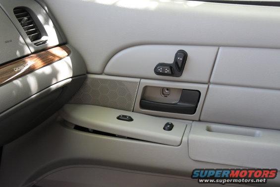 Car door panel with seat controls, window switches, and a wood trim accent. Text on trim reads 'Crown Victoria'