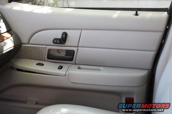 Light tan car interior door panel with power window and seat controls, black door handle, and speaker grille