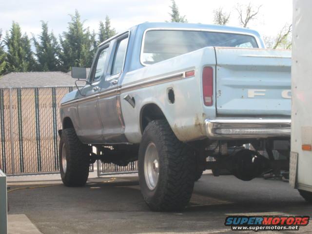 Light blue and white Ford F-250 truck, lifted, with chrome bumper and visible rear axle