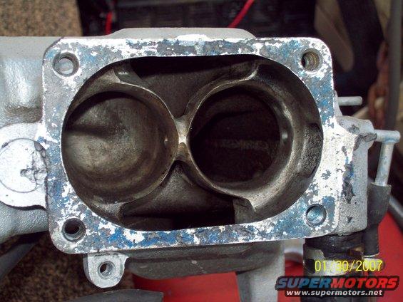 Close-up of two intake manifold ports with blue paint chipping around the flange