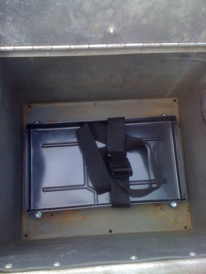 Battery tray with strap inside a metal compartment
