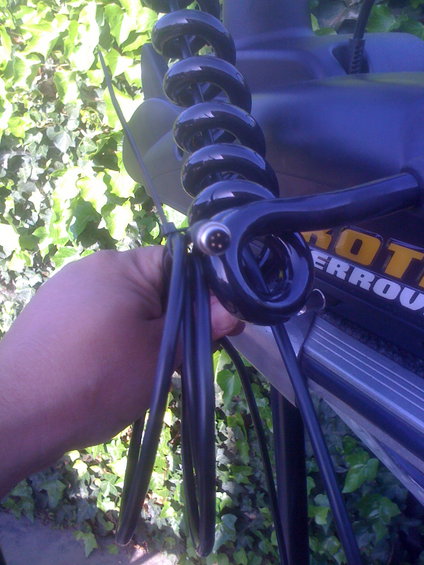 Hand holding black coiled cable and connector near a trolling motor with yellow text