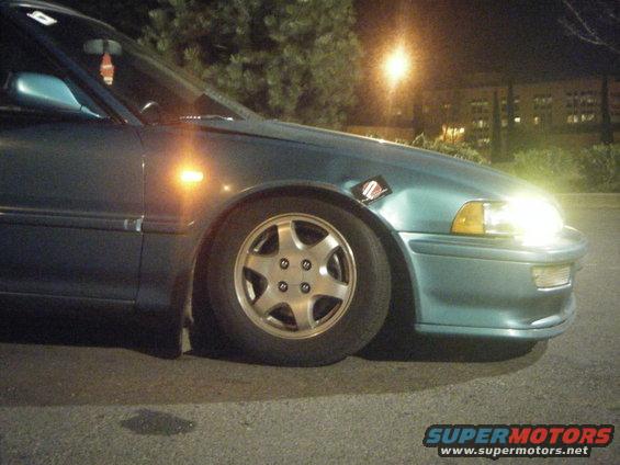Teal sedan front fender and wheel, with a sticker on the fender