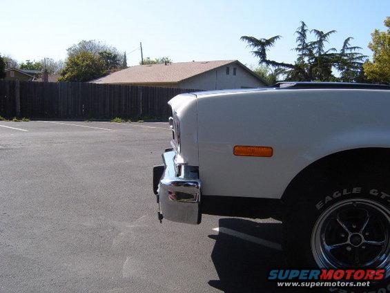 White car front corner with chrome bumper and orange turn signal. Eagle GT tire visible
