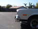 1973 Ford Ranchero - The front corner of a white vehicle is shown from a low angle, revealing a chrome bumper and an orange turn signal.