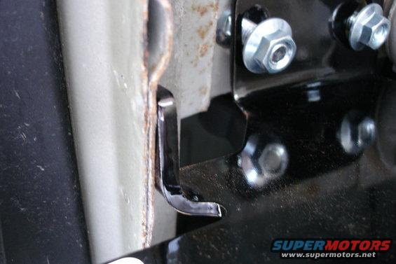 Close-up of a black metal hitch bracket bolted to a vehicle frame with silver bolts