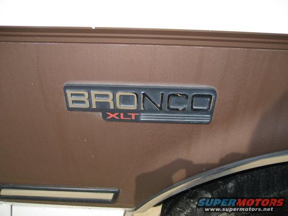 Close-up of a Bronco XLT emblem on a brown vehicle panel