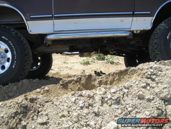 side view of a lifted SUV with off-road tires driving over dirt mounds