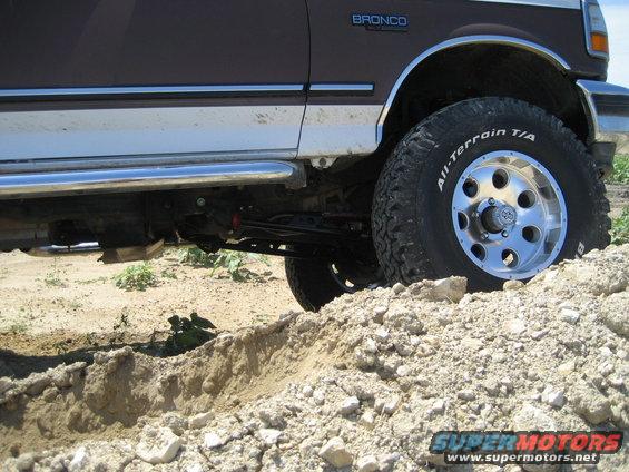 1993 Ford Bronco side view, driving through dirt and rocks. All-Terrain T/A tires