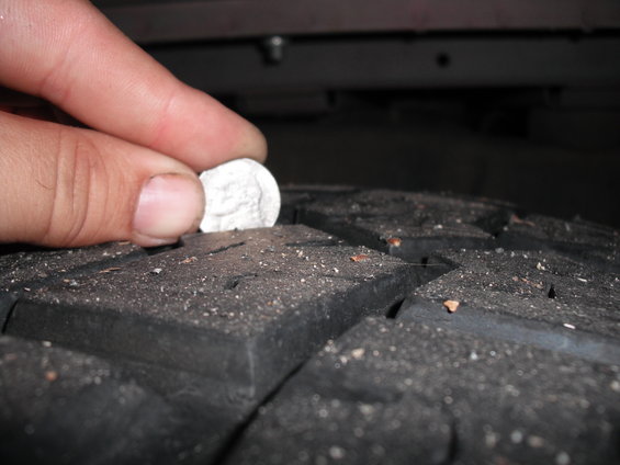 Tire tread with a dime inserted to check depth
