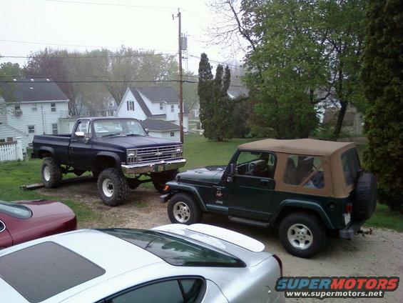Dark blue lifted pickup truck, front 3/4 view