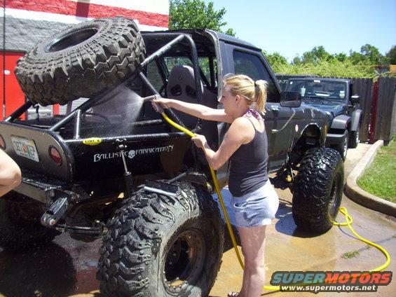 Black off-road vehicle with spare tire on back being washed