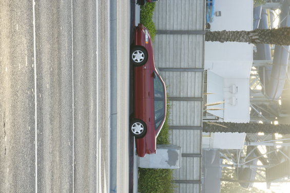 Red 1992 Ford Taurus sedan parked by a concrete wall