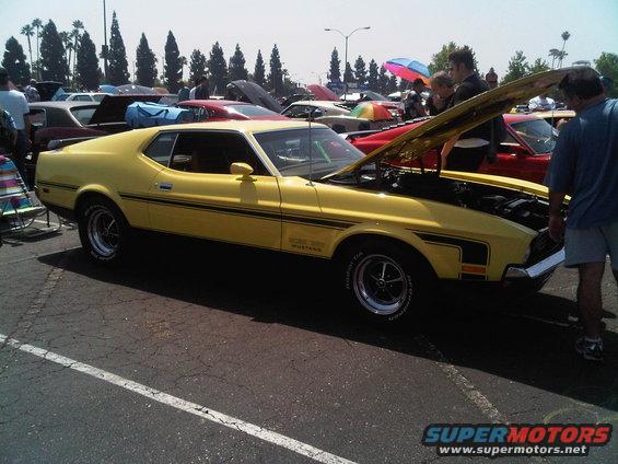 Yellow 1971 Ford Mustang Mach 1 with hood open at a car show