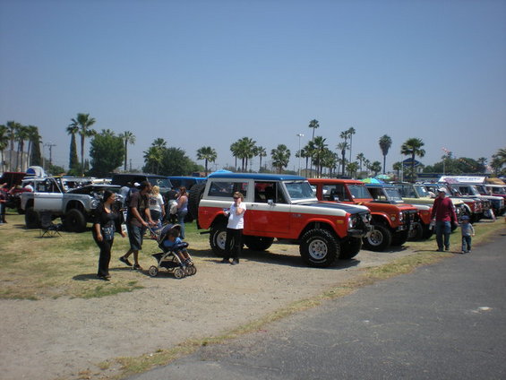 Orange and blue Ford Bronco parked in a lot with other vehicles and people