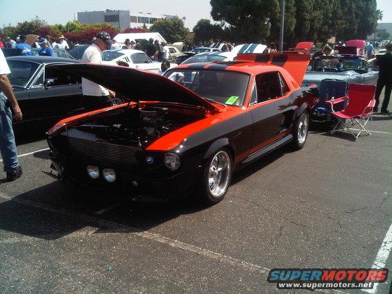 Black and orange 1967 Ford Mustang with hood open at a car show